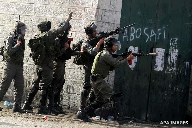 An Israeli security officer fires tear gas towards Palestinian protesters during clashes next to the Israeli military prison 'Ofer' in Beitunya, south of the West Bank city of Ramallah, on February 24, 2013 following the...