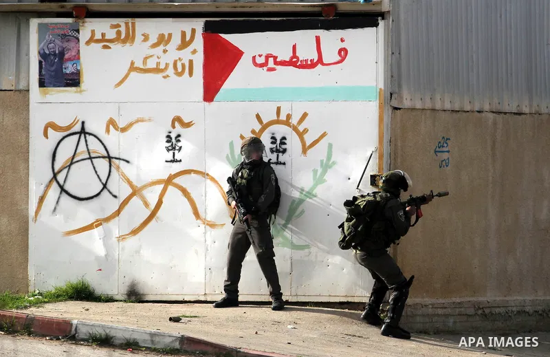 An Israeli security officer fires tear gas towards Palestinian protesters during clashes next to the Israeli military prison 'Ofer' in Beitunya, south of the West Bank city of Ramallah, on February 24, 2013 following the...
