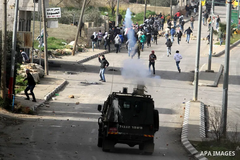 Israeli security forces fire tear gas towards Palestinian protesters during clashes next to the Israeli military prison 'Ofer' in Beitunya, south of the West Bank city of Ramallah, on February 24, 2013 following the deat...