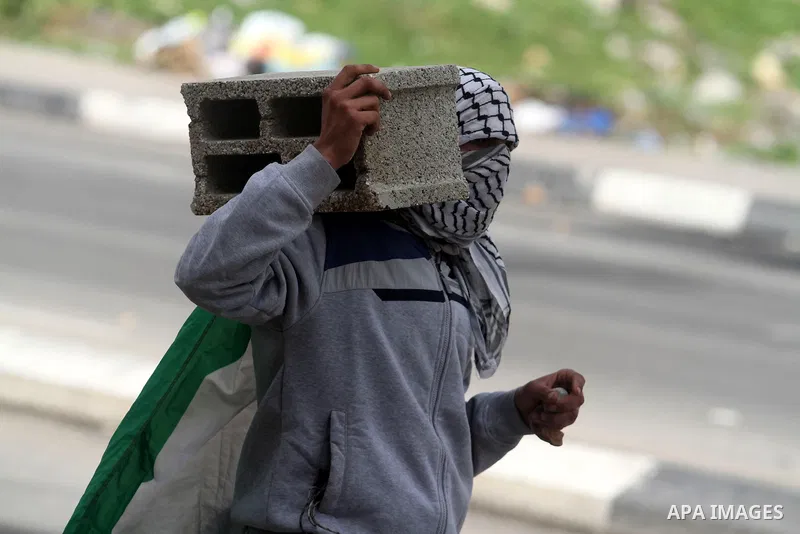 A Palestinian protester carries a cement block during clashes next to the Israeli military prison 'Ofer' in Beitunya, south of the West Bank city of Ramallah, on February 24, 2013 following the death of a Palestinian pri...
