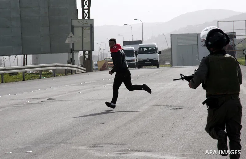 An Israeli border officer runs after a Palestinian protester during clashes at Hawwara military checkpoint near the West Bank city of Nablus, on February 24, 2013 following the death of a Palestinian prisoner held in Isr...