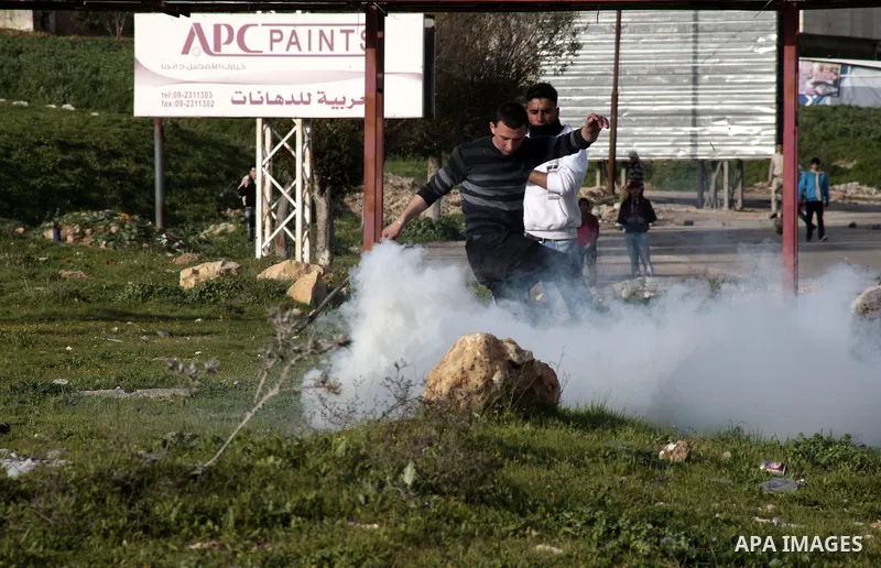 A Palestinian protester throws back a tear gas canister fired by Israeli border police during clashes at Hawwara military checkpoint near the West Bank city of Nablus, on February 24, 2013 following the death of a Palest...