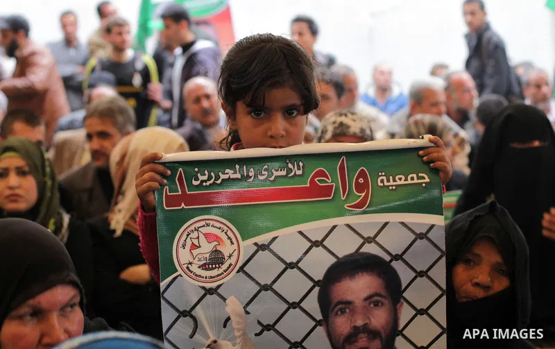 Palestinians hold pictures of prisoners held in the Israeli jails during a protest calling for the release of Palestinian prisoners from Israeli jails in front of the Red cross office in Gaza city, on February 25, 2013....