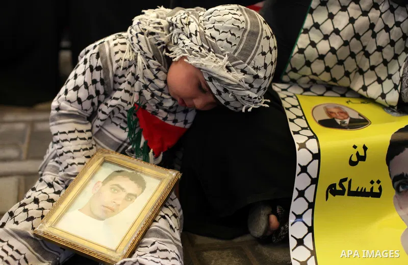 Palestinians hold pictures of prisoners held in the Israeli jails during a protest calling for the release of Palestinian prisoners from Israeli jails in front of the Red cross office in Gaza city, on February 25, 2013....