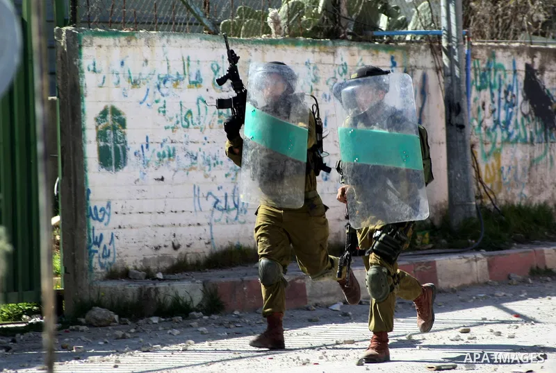 Israeli security forces take cover during clashes with Palestinian protesters in al-Aroob refugee camp near the West Bank town of Hebron on February 26, 2013. Increased protests in the West Bank after the killing of a Pa...