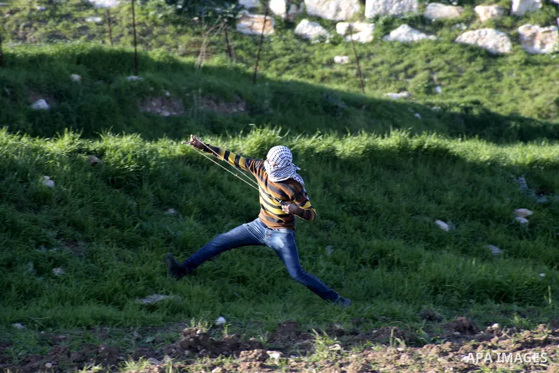 A Palestinian protester hurls stones at Israeli security forces during clashes at Hawwara military checkpoint near the West Bank city of Nablus on February 26, 2013. Increased protests in the West Bank after the killing...