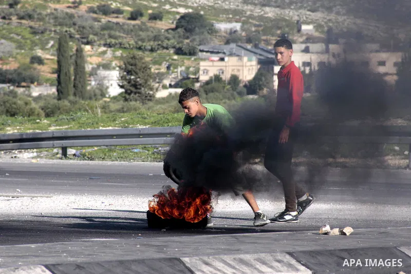 A Palestinian protester burns a tire during clashes with Israeli security forces at Hawwara military checkpoint near the West Bank city of Nablus on February 26, 2013. Increased protests in the West Bank after the killin...