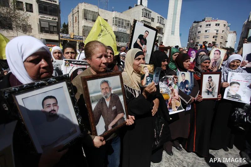 Palestinians carry portraits of prisoners in Israeli jails during a rally organized by the Ministry of prisoners in solidarity with Palestinian prisoners on hunger strike,in the West Bank city of Ramallah on February 27,...