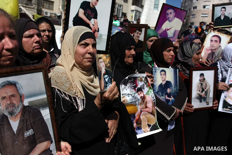 Palestinians carry portraits of prisoners in Israeli jails during a rally organized by the Ministry of prisoners in solidarity with Palestinian prisoners on hunger strike,in the West Bank city of Ramallah on February 27,...