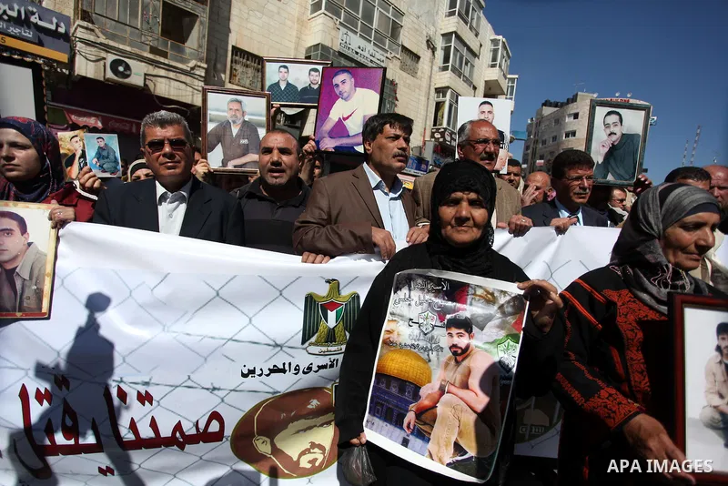 Palestinians carry portraits of prisoners in Israeli jails during a rally organized by the Ministry of prisoners in solidarity with Palestinian prisoners on hunger strike,in the West Bank city of Ramallah on February 27,...