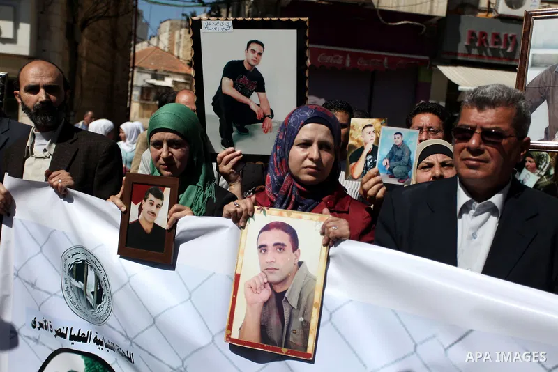 Palestinians carry portraits of prisoners in Israeli jails during a rally organized by the Ministry of prisoners in solidarity with Palestinian prisoners on hunger strike,in the West Bank city of Ramallah on February 27,...