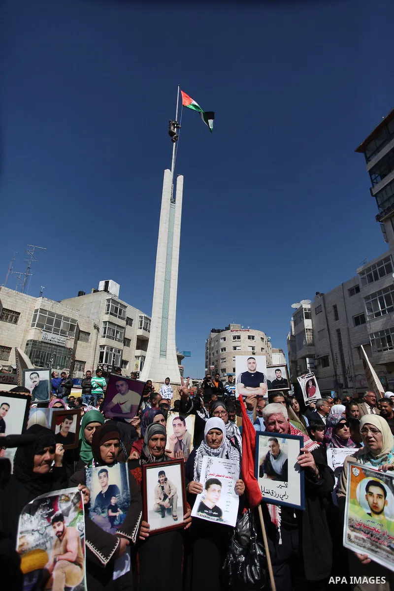 Palestinians carry portraits of prisoners in Israeli jails during a rally organized by the Ministry of prisoners in solidarity with Palestinian prisoners on hunger strike,in the West Bank city of Ramallah on February 27,...