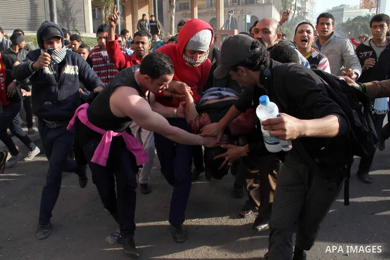 Egyptian protesters carry their gravely injured comrade during clashes with riot police near Tahrir Square in Cairo on March 9, 2013. Egyptian football fans protested violently on 09 March after a court upheld 21 death s...