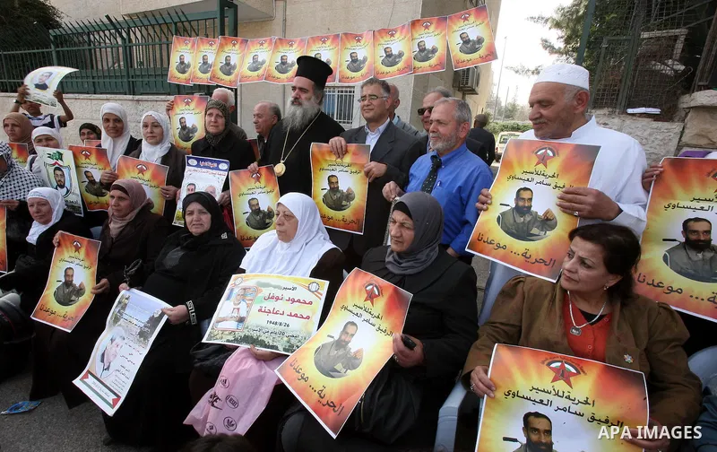 Palestinians hold pictures of prisoners held in Israeli jails during a sit-in outside the Red Cross offices in Jerusalem, in solidarity with hunger-striking detainees held by Israel to demand their release from detention...