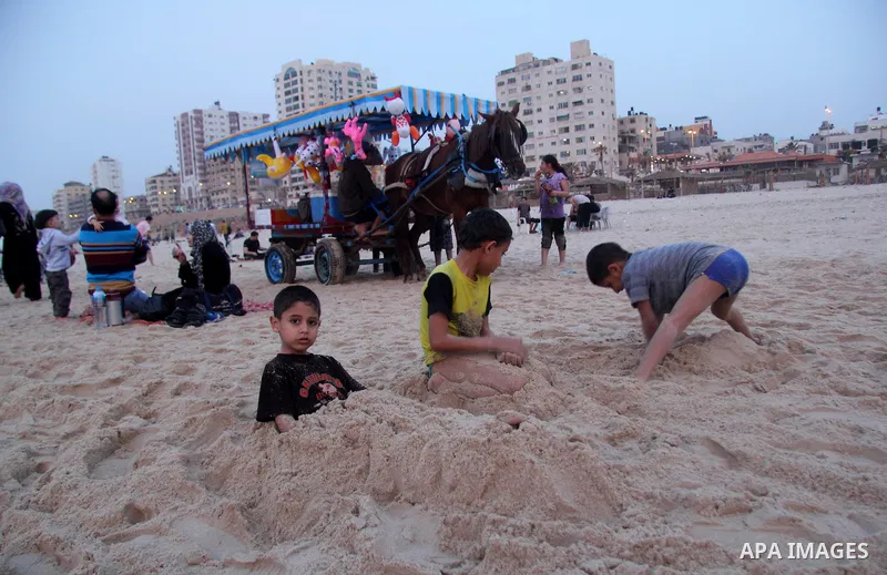 Palestinian children enjoy playing in the sea at Gaza beach during hot weather in Gaza city, March 15, 2013. The temperature of the Gaza strip reaches more than 30 degrees Celsius, Gazans escape to the beach and out from...