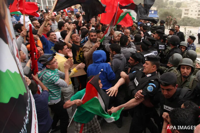 Palestinian security forces stand guard in front of protesters waving flags during a protest in the Dheisheh refugee camp, near the West Bank city of Bethlehem on 22 March 2013, against the visit of US President Barack O...