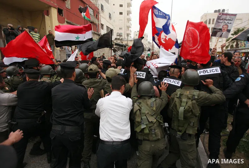 Palestinian security forces stand guard in front of protesters waving flags during a protest in the Dheisheh refugee camp, near the West Bank city of Bethlehem on 22 March 2013, against the visit of US President Barack O...