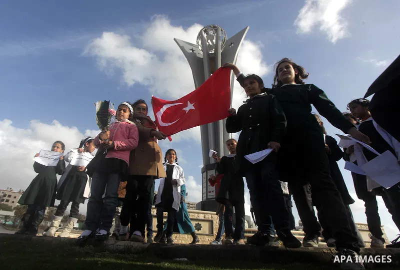 Palestinian schoolgirls hold Turkish flag and gather next to a statue erected as a memorial for the victims of the Turkish flotilla Mavi Marmara in the port of Gaza City on March 23, 2013. Israeli Prime Minister Benjamin...