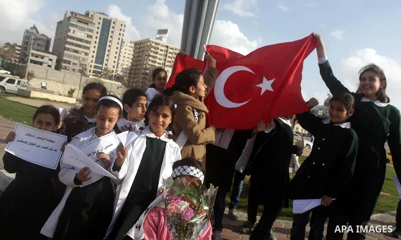 Palestinian schoolgirls hold Turkish flag and gather next to a statue erected as a memorial for the victims of the Turkish flotilla Mavi Marmara in the port of Gaza City on March 23, 2013. Israeli Prime Minister Benjamin...