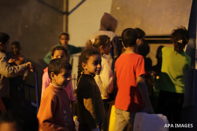 Palestinian boys and girls stand in line holding container as they wait to fill with fresh water from the desalination station in Deir al-Balah refugee camp in the center of the Gaza Strip on March 26, 2013. Photo by Ash...