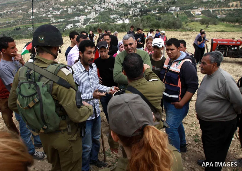 Israel soldiers stand guards as they prevent Palestinians and foreign activists from planting olive trees marking Land Day in the West Bank Village of Burin near Nablus on March 30, 2013. Land Day commemorates the killin...