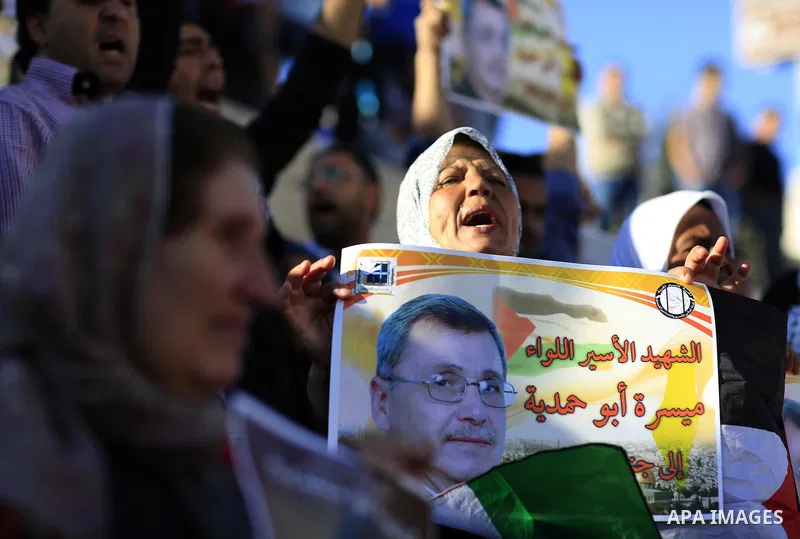 Palestinian hold-up pictures of Maisara Abu Hamdiyeh, a prisoner who died of cancer while being held by in an Israeli jail, during a protest against his death at the entrance of Jerusalem's Old City next to the Damascus...