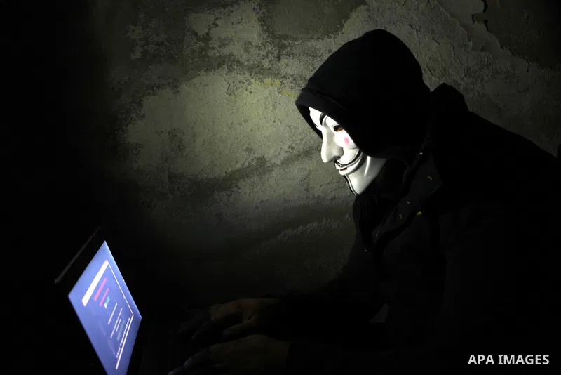 A Palestinian youth wearing masks used by computer hackers who attacked a number of Israeli websites recently, seen backdropped by the Dome of the Rock, in Jerusalem's Old City. April 08 2013. Photo by Sliman Khader