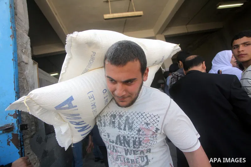 A Palestinian man carries a sack of flour inside a United Nations food distribution centre in Gaza City April 10, 2013. The main U.N. humanitarian agency for Palestinians said on Monday it was reopening its Gaza food dis...
