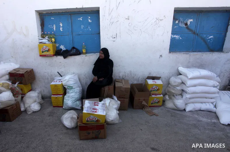 A Palestinian refugee rests next to a flour sack received from United Nations Relief and Works Agency (UNRWA) inside a United Nations food distribution centre in Gaza City April 10, 2013. The main U.N. humanitarian agenc...
