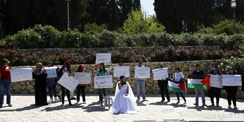 An Israeli Arab young woman wears a bridal gown as she plays the part of a bride without her groom as they pass the Rose Garden on their way to the Jerusalem offices of Israeli Prime Minister Benjamin Netanyahu, 14 April...