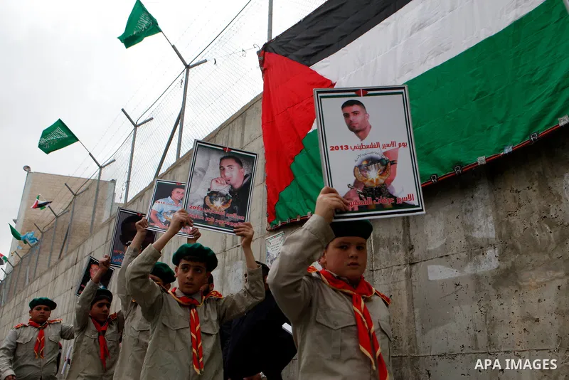Palestinian scouts members carry pictures of prisoners during a rally in support with prisoners jailed in Israeli prisons in Jerusalem on April 19, 2013. Israeli President Shimon Peres pardoned on April 13 a Palestinian...