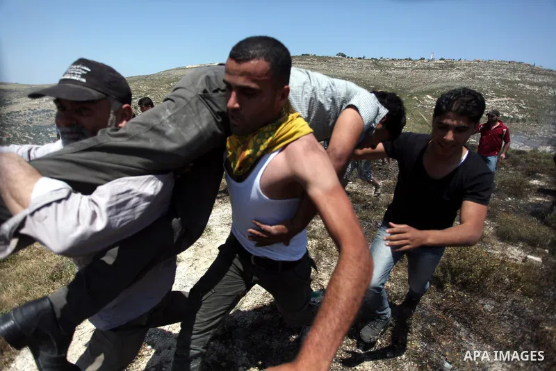 Palestinian villagers help a wounded man during clashes Jewish settlers in Oref village near Nablus City 30 April 2013. Reports state that the clashes occured after an Israeli settler was stabbed to death by a Palestinia...