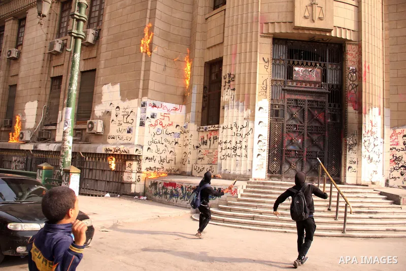 Egyptian masked members of the Black Bloc movement throw molotov cocktail at the High court building, in Cairo on May 03, 2013. Photo by Tareq Gabas