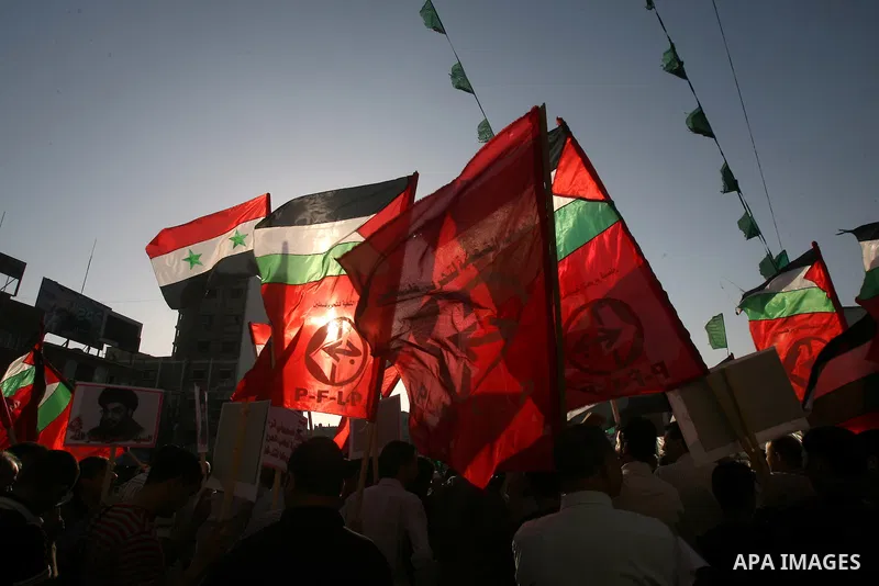 Palestinian supporters of leftist parties hold pictures of the leader of the Shiite Muslim group Hezbollah, Hassan Nasrallah, and Syrian flags during a protest against Israeli air strikes close to Damascus, in Khan Youni...