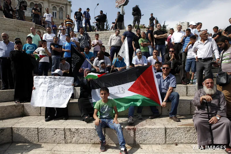 Palestinian protesters hold their national flag as Israeli Jewish settlers celebrate Jerusalem Day that marks the anniversary of the reunification of the holy city in front of the Damascus gate on May 8, 2013 in Jerusale...