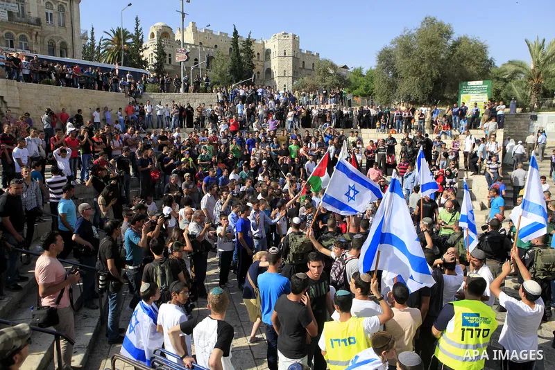 Israelis and Palestinians hold their flags as they protest against each other during a Palestinian demonstration against the Jerusalem Day that marks the anniversary of the reunification of the holy city in front of Dama...
