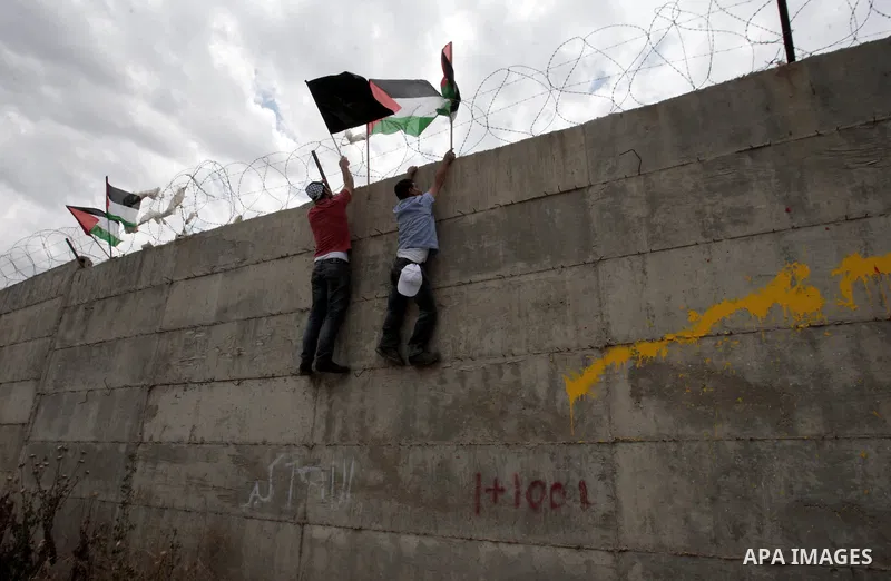 Palestinian demonstrators place a Palestinian flag on Israel's separation barrier during a march ahead of Nakba in the West Bank city of Tulkarem on May 13, 2013. Palestinians and Arab Israelis are preparing to mark Nakb...
