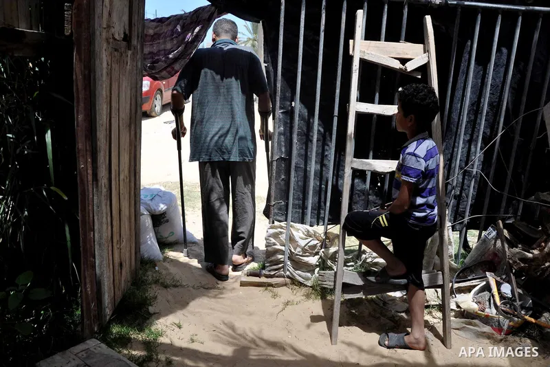 Palestinian Bassem Farwaneh walks at his house in Khan Younis in southern Gaza Strip, May 14, 2013. Farwaneh is a disabled man after he was targeted by Israeli troops, sustenance to provide his sick children and live in...