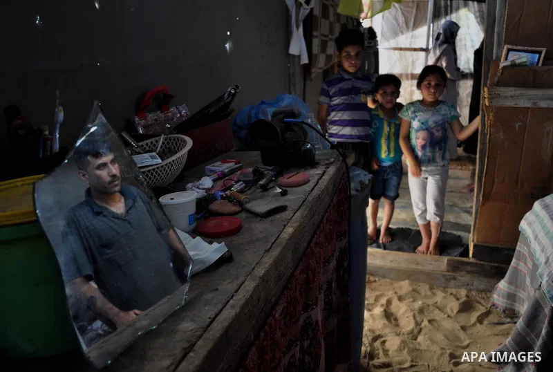 Palestinian Bassem Farwaneh looks through a mirror at his house in Khan Younis in southern Gaza Strip, May 14, 2013. Farwaneh is a disabled man after he was targeted by Israeli troops, sustenance to provide his sick chil...