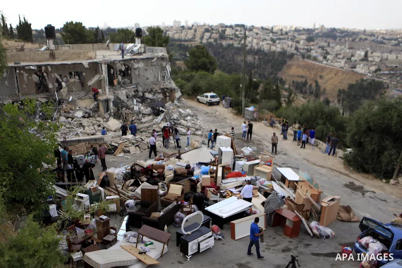 Palestinians search through the remains of the demolished house after it was demolished by Israeli bulldozers in the neighborhood of al-Tur in Israeli-occupied east Jerusalem on May 21, 2013, in implementation of a court...