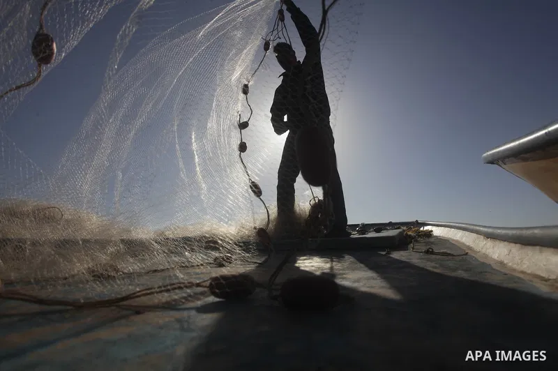 A Palestinian fisherman loads a net into their boat at the port in Gaza City, Tuesday, May 21, 2013. Israel on Tuesday expanded the distance it permits Gaza fishermen to head out to sea from 3 miles to 6 miles, restoring...
