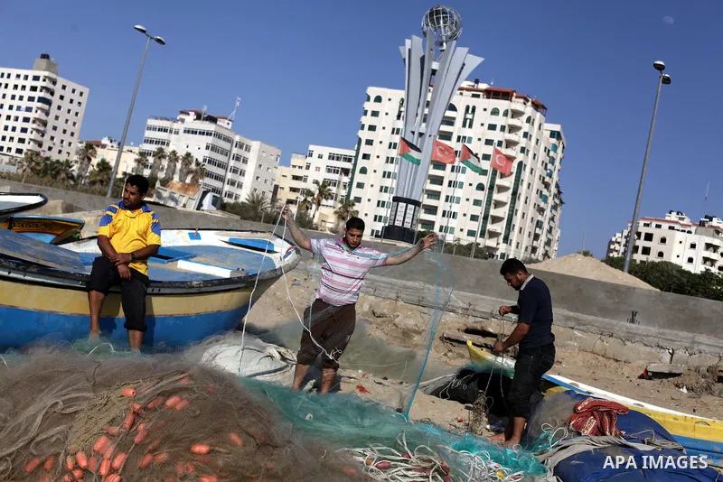 Palestinian fishermen load a net into their boat at the port in Gaza City, Tuesday, May 21, 2013. Israel on Tuesday expanded the distance it permits Gaza fishermen to head out to sea from 3 miles to 6 miles, restoring a...