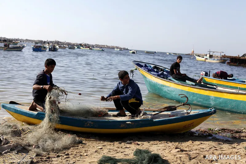 Palestinian fishermen load a net into their boat at the port in Gaza City, Tuesday, May 21, 2013. Israel on Tuesday expanded the distance it permits Gaza fishermen to head out to sea from 3 miles to 6 miles, restoring a...