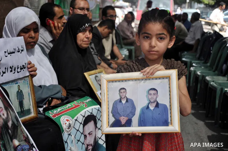 Palestinians hold pictures of prisoners held in Israeli jails during a protest in Gaza City, on May. 23, 2013 in solidarity with Palestinian prisoners on hunger strike in Israeli jails. Photo by Mohammed Talatene