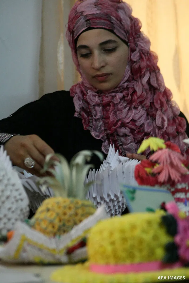 A Palestinian woman, 26-year-old Fadia Zahdeh, works on paper decorations that she created through the re-use of waste paper, to sell as gifts and to establish a small business, in the West Bank city of Hebron on May 23,...
