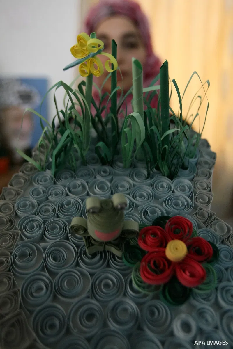 A Palestinian woman, 26-year-old Fadia Zahdeh, works on paper decorations that she created through the re-use of waste paper, to sell as gifts and to establish a small business, in the West Bank city of Hebron on May 23,...