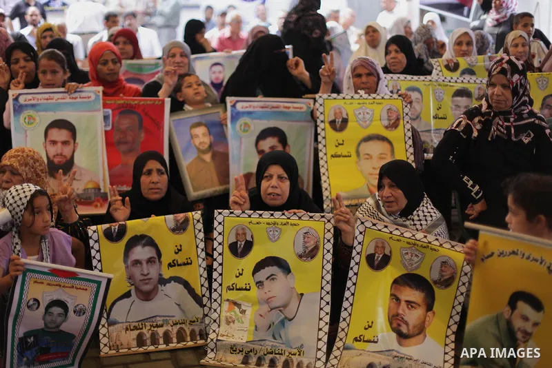 Palestinians hold pictures of prisoners held in Israeli jails during a protest at inside Red Cross office in Gaza City, on May. 27, 2013 in solidarity with Palestinian prisoners held by Israel to demand their release fro...