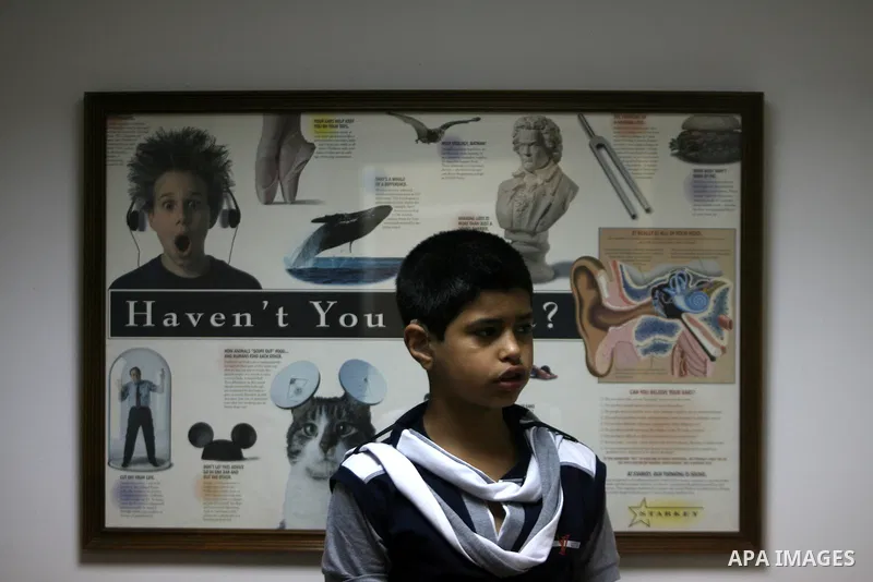 A Palestinian deaf boy shows his ear hearing aid at a deaf center in preparation for implant a cochlear, in Gaza city on May 27, 2013. Cochlear implants may help provide hearing in patients that are not deaf because of d...