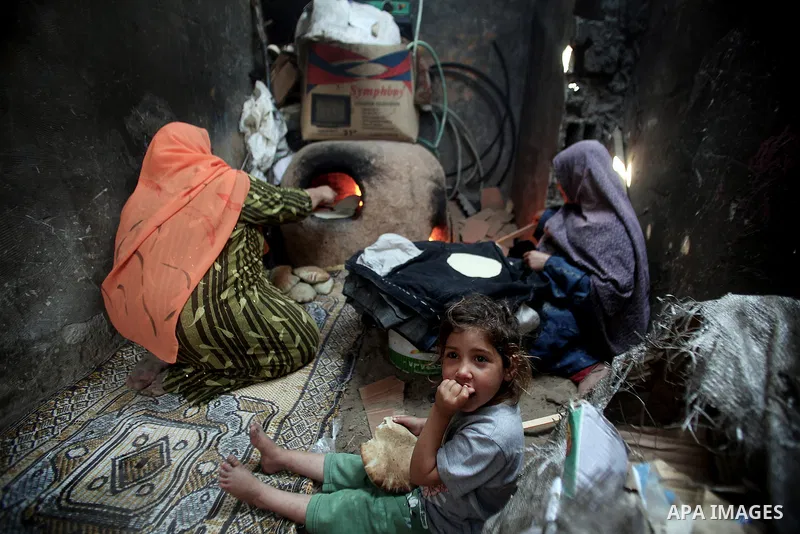 Palestinian women bake bread on firewood outside their family house in Beit Lahiya town, North Gaza Strip, 28 May 2013. Photo by Ali Jadallah