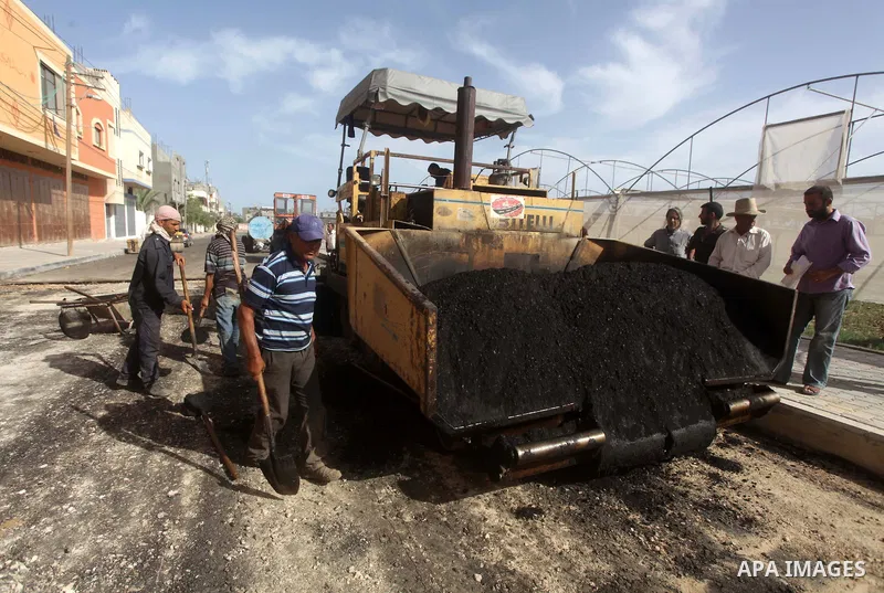 Palestinian workers lay asphalt as a street is paved in Deir al-Balah in central Gaza Strip, on May 29, 2013. Photo by Ashraf Amra